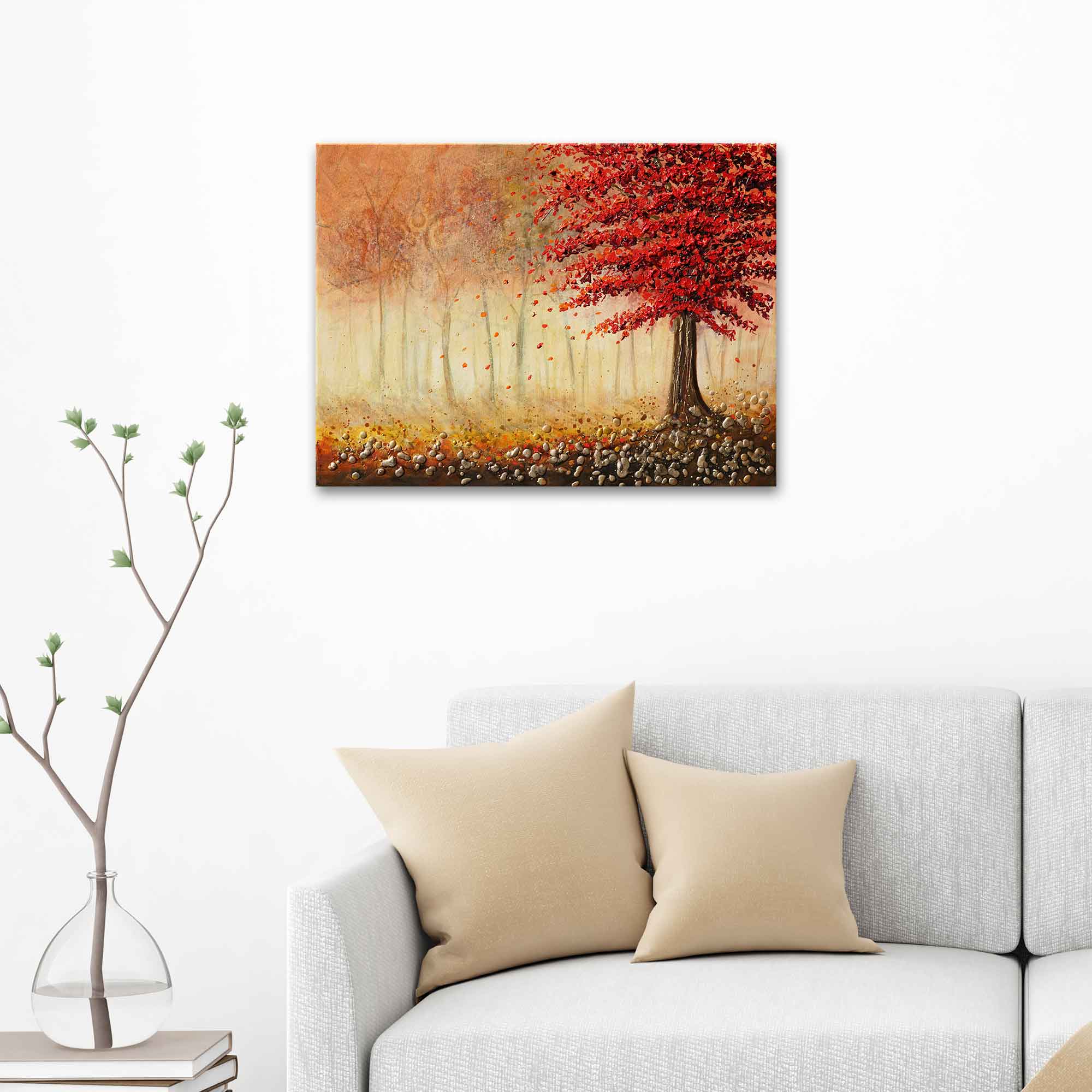 Painting of a red tree in a forest above a gray sofa with beige pillows.