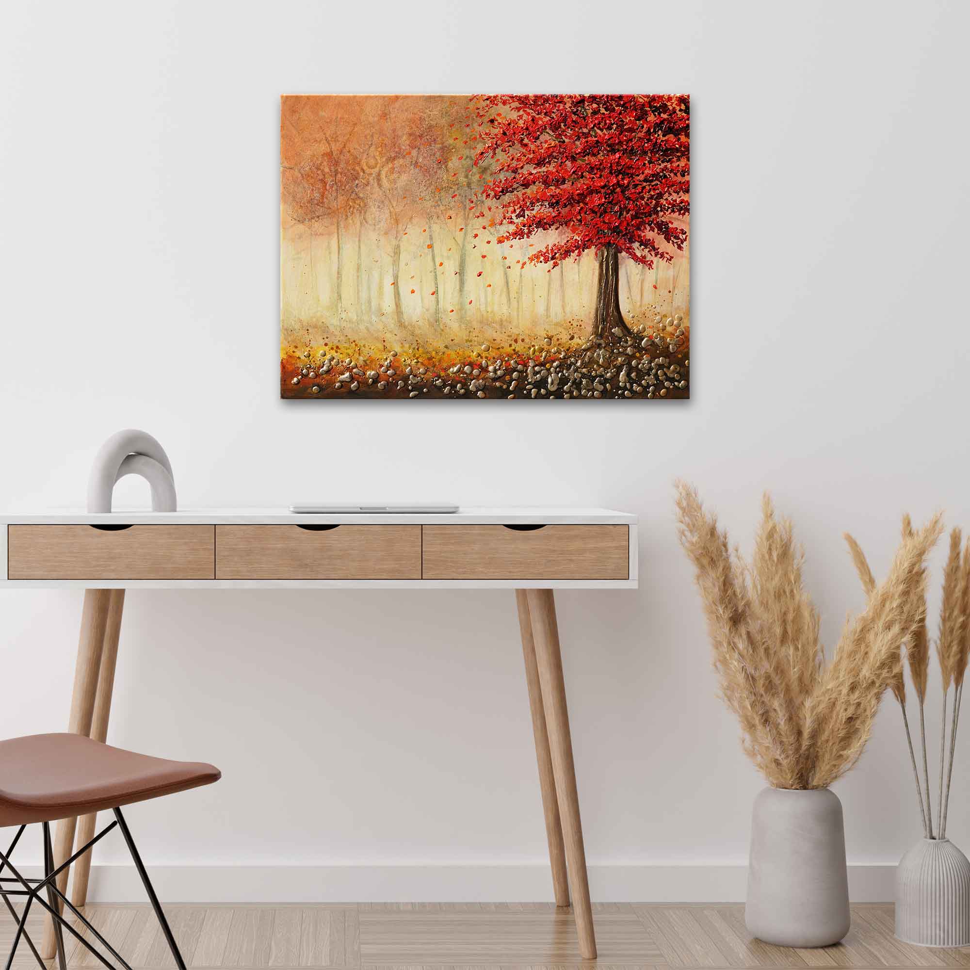 Painting of a red tree in an autumn forest above a wooden desk with decorative elements.